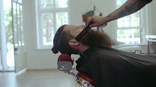 Hairdresser serving client with big beard
