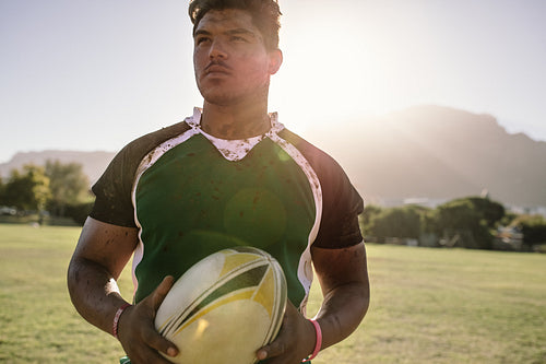 Rugby player holding a ball on ground