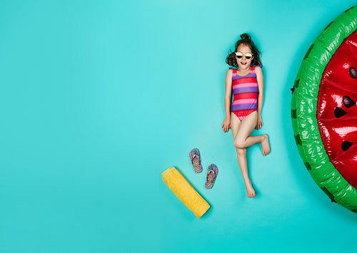 Happy girl in swimsuit relaxing on blue background