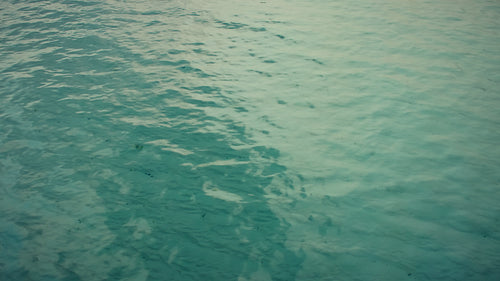 Clear tranquil water surface shimmering with blue and green, reflecting light and peacefulness