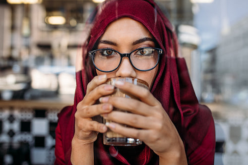 Muslim woman having coffee at cafe