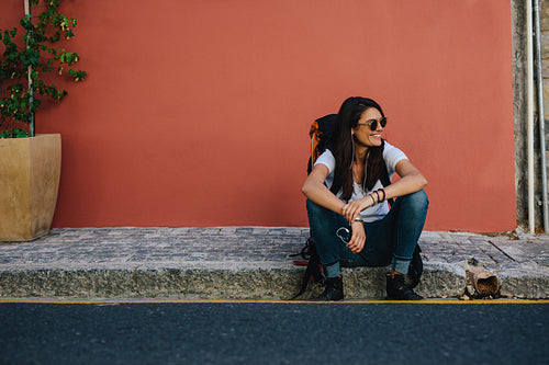 Female traveler resting on the sidewalk
