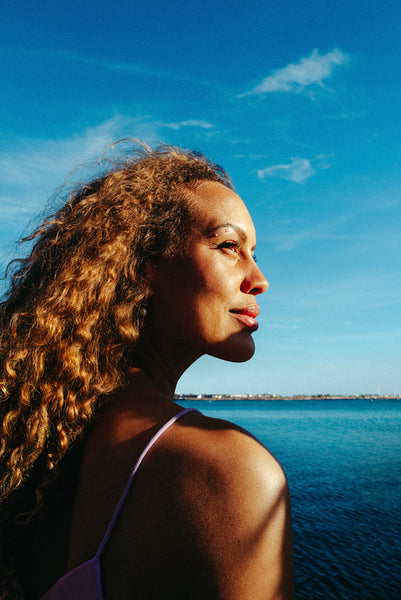 Woman gazes at the horizon under summer sun by the sea