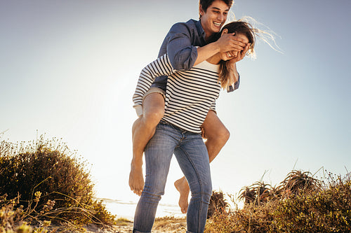 Man piggy riding on his girlfriend closing her eyes with his hands