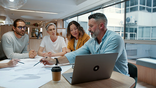 Architects working together on a project, discussing a set of blueprints and plans in a meeting