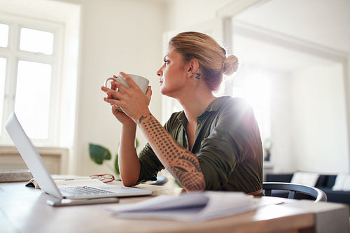 Young woman with coffee looking away and thinking