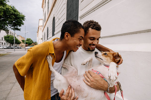 Happy couple joyfully playing with their dog outdoors on a sunny day