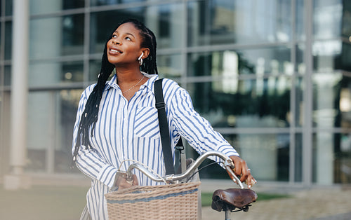 Thoughtful young businesswoman commuting with a bicycle in the city
