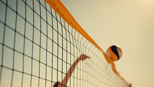 Professional female volleyball player spiking ball at beach championship