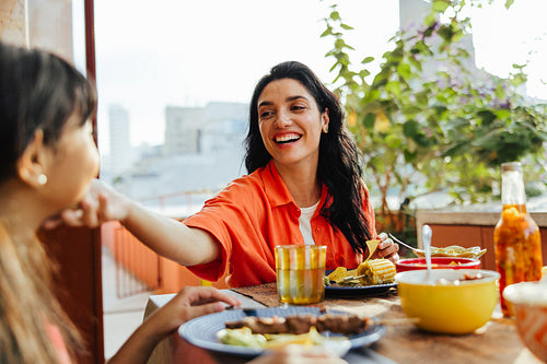 Mother and daughter enjoying a meal together in a sunny outdoor setting