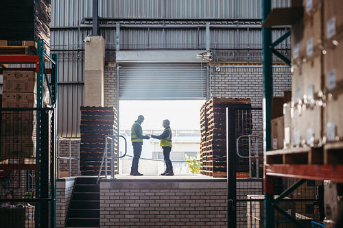 Happy logistics workers signing a dock receipt while standing on a loading dock
