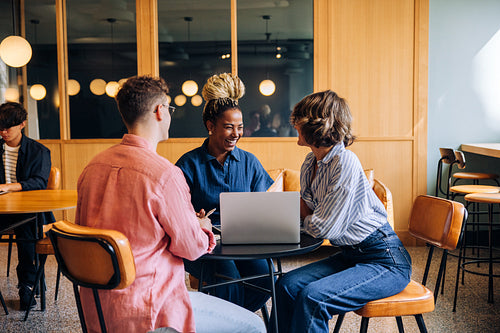 Young coworkers discussing ideas with a laptop in a coworking setting