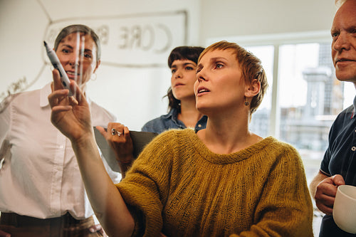 Group of colleagues brainstorming together on a glass wall in of