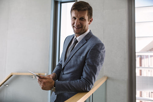 Businessman in office corridor with digital tablet