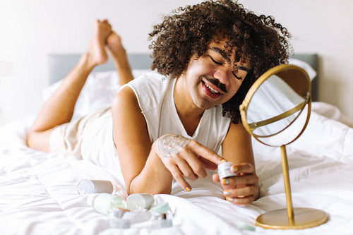 Gender nonconforming man applying makeup at home