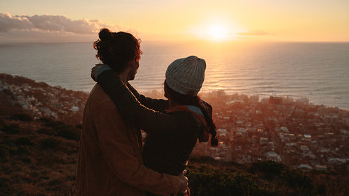 Romantic couple admiring the sunset from peak
