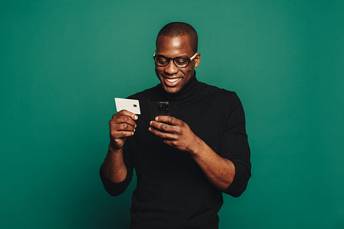 Young man using a credit card for online shopping with his smartphone