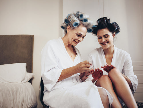Happy mother and daughter doing manicure sitting at home