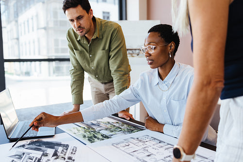 Three colleagues discussing architectural design concepts together in a modern office setting