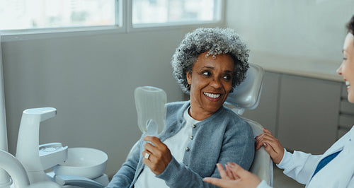 Senior patient holding dental mirror during consultation with dentist