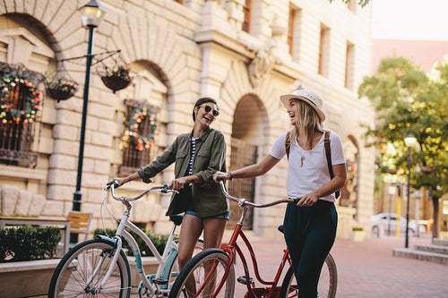 Friends walking with bicycles on street