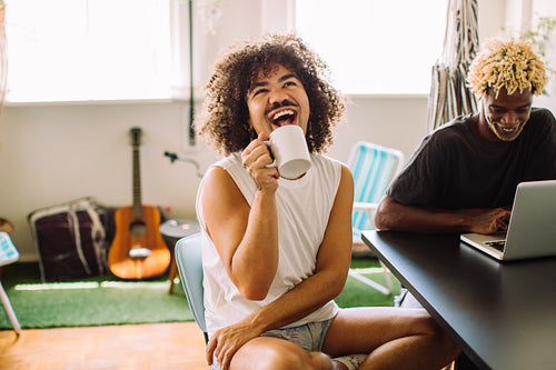 Gay man laughing while sitting with his lover at home