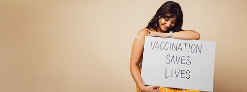 Woman holding a banner of "vaccination saves lives" slogan