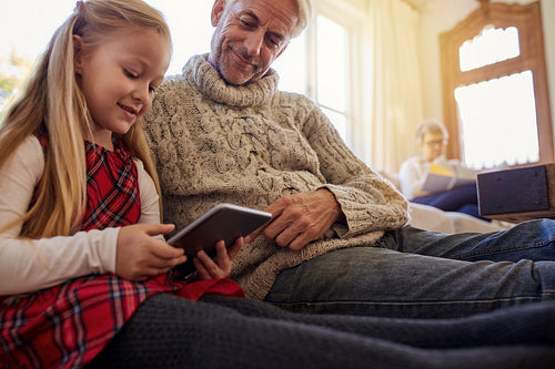 Little girl with grandfather using tablet pc at home