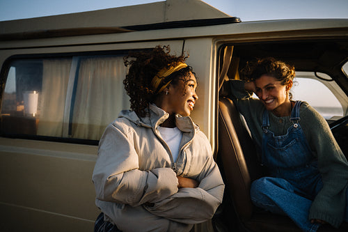 Two friends share a joyful moment in a van during sunset