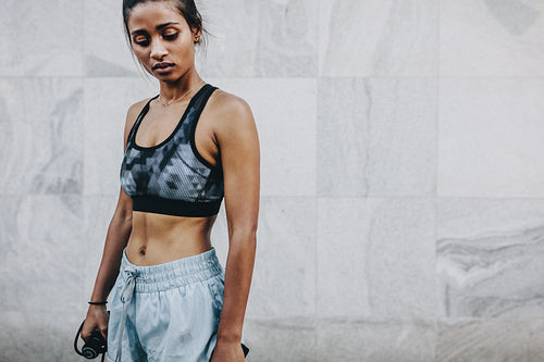 Fitness woman standing outdoors holding skipping rope