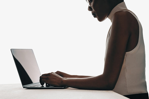 Side view of woman working on a laptop in minimalist setting