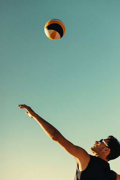Beach volleyball player in action during championship game with arms raised on coastal beach