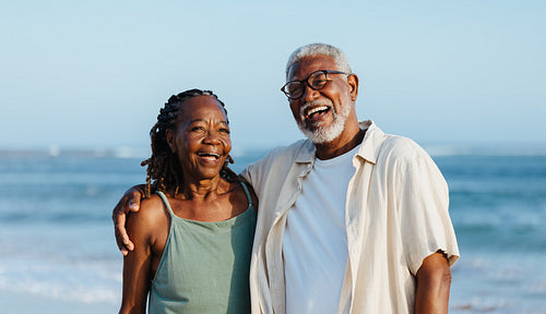 Joyful elderly black couple walking on a beach
