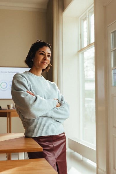 Businesswoman stands with crossed arms in office