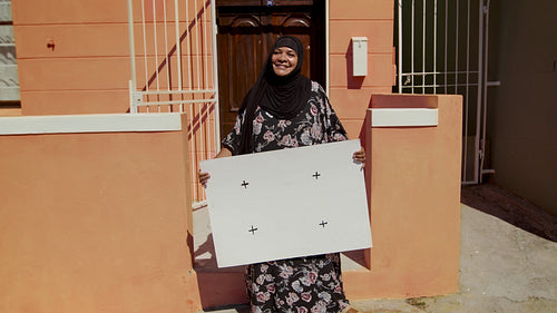 Smiling senior muslim woman with blank billboard outside