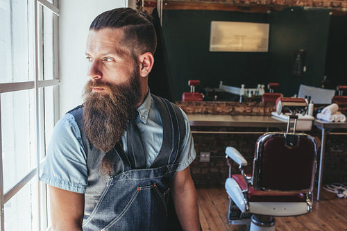 Barber standing by window and looking away