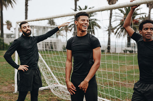 Footballers standing near the goalpost relaxing
