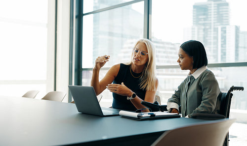 Two businesswomen discussing plans in a modern office setting