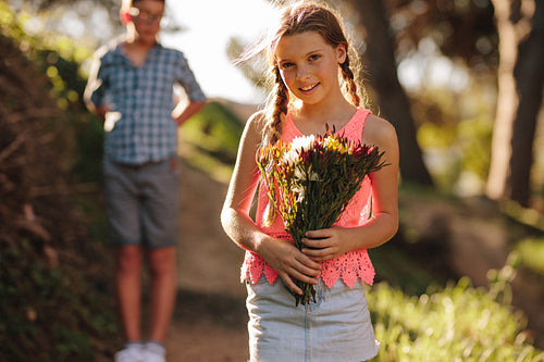 Girl standing in park holding a bunch of flowers