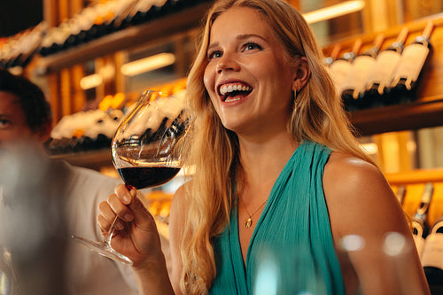 Blonde woman with long hair laughing and holding a glass of wine at a wine tasting event