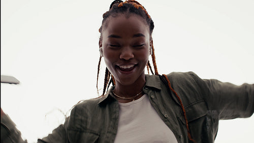 Energetic young woman dancing joyfully with wireless earbuds and a mobile phone in a studio