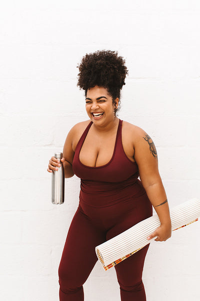 Happy woman with yoga mat and water bottle