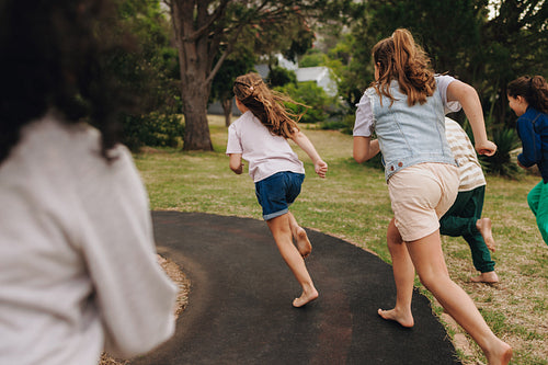 Children playing and running together through a park pathway on a sunny day
