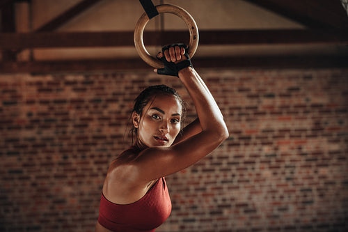 Sporty woman exercising with gymnastic rings at gym