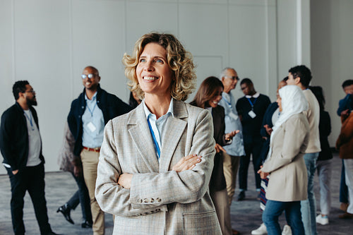 Mature successful businesswoman in office environment with colleagues in the background