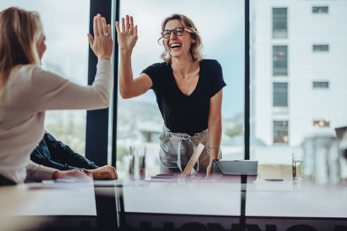 Businesswomen high five in a board room meeting