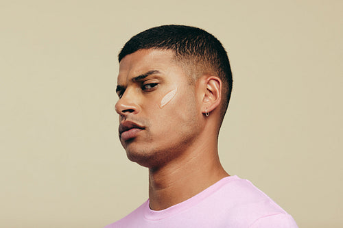 Young man looking at the camera with skin serum on his face