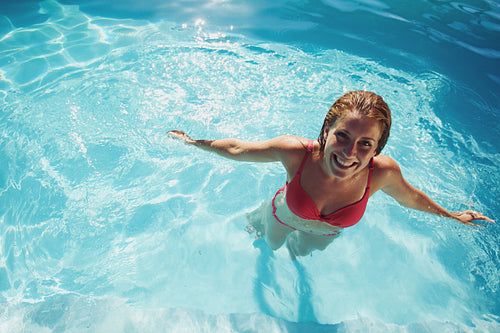 Girl standing in a swimming pool smiling