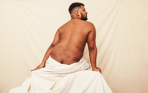 Naked man sitting in a studio