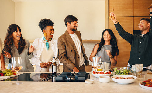 Friends celebrating with food and drinks in a kitchen together